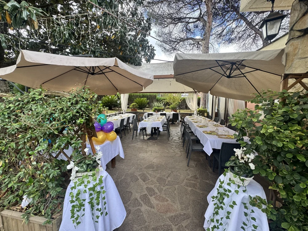 La terrazza di Mama’s Restaurant, con tavoli apparecchiati tra alberi e ombrelloni